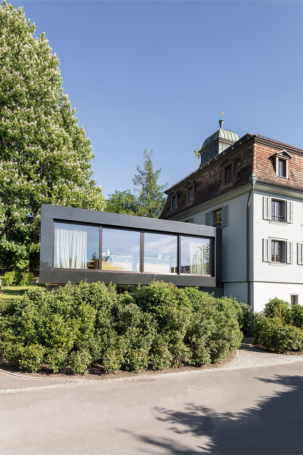 Eine Fassade aus Naturstein mit kubischer Terrassenüberdachung